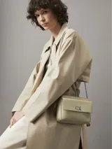 Bandolera rectangular color verde claro, con correa de cadena plateada y logo CK plateado en el frente.