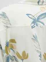 Camisa de manga corta con cuello resort y calce relajado. Confeccionada en viscosa, presenta un estampado floral en tonos azules y verdes sobre fondo color crema.