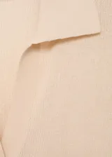 Jersey de punto fino color beige, con cuello camisero, cierre frontal de botones y manga corta. Diseño entallado con textura de canalé.