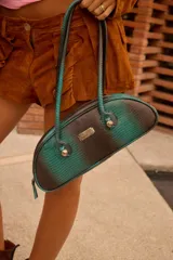 Cartera estilo baguette de cuero, con diseño estructurado y silueta alargada. Presenta manijas largas con detalles de nudos esféricos metálicos en la unión.