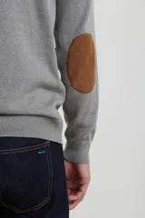 Sweater de punto gris con medio cierre frontal, cuello alto y coderas en tono marrón. Presenta un diseño clásico con puños y ruedo acanalados.