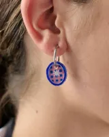 Dije colgante circular de acrílico con borde azul y centro estampado en tonos rosados y azules con diseño de estrella central.