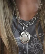 Collar plateado con cadena de eslabones grandes y dije irregular con centro liso.
