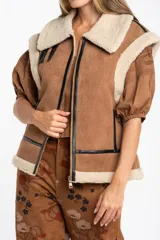 Chaleco estilo gamulán de color negro, con interior y cuello de corderito sintético. Presenta cierre frontal, detalles en cuero sintético y corte oversize.