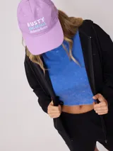 Gorro de visera color lila, estilo dad hat, de lona lavada con bordado frontal en blanco que dice "RUSTY AUSTRALIA MERMAID BEACH".