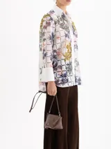 Bandolera de cuero vacuno con silueta estructurada, cierre superior y aplique metálico frontal. Incluye correa regulable y tag colgante con detalle decorativo.