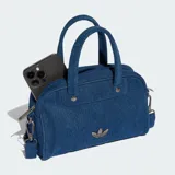 Minibolsa tipo bowling de Adidas Originals confeccionada en denim azul, con asas superiores, correa de hombro desmontable, cierre de cremallera y detalle del logo Trefoil metálico en el frente.