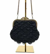 Bolso tipo sobre de estilo vintage, bordado íntegramente con mostacillas negras formando un patrón de ondas. Presenta una boquilla metálica dorada con cierre a presión y una cadena fina dorada para llevar al hombro.