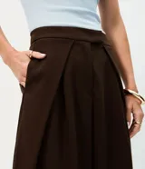 Pantalón de sastrería en crepé color marrón, de modelaje barrel y tiro alto con cintura estructurada. Presenta pinzas frontales profundas, bolsillos embutidos y caída amplia de corte recto.
