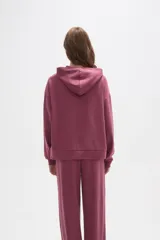 Canguro con capucha de calce holgado, color bordó, con detalle de aplique de strass en el pecho.