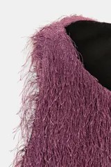 Top de cuello redondo y manga sisa, confeccionado con un acabado de flecos largos en color lila. Presenta un diseño recto con cierre en la espalda mediante abertura y botón oculto.