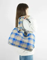Bolso tipo tote bag de franela a cuadros en tonos azul y beige, con asas tubulares acolchadas y cierre con cordón ajustable.