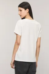 Remera de jersey de algodón blanca con calce regular, cuello redondo y mangas cortas. Presenta una estampa frontal con la leyenda "The Rocking Lovers" y una imagen de un cenicero en forma de corazón con cigarrillos.