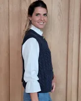 Chaleco de punto con diseño de trenzas, color gris oscuro, con cierre frontal de botones grandes y bolsillos laterales.