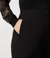 Pantalón negro de vestir, tiro alto, corte wide leg (pierna ancha), con bolsillos laterales y cierre frontal con cremallera y gancho.