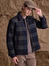 Chaqueta de lana con cierre frontal completo, diseño a cuadros en tonos azul marino y verde, cuello camisero y bolsillos laterales.