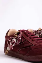 Zapatillas urbanas de gamuza color marrón, con diseño de cordones decorados con cuentas de piedra y detalles de líneas brillantes en los laterales. Presentan suela de goma texturizada al tono.