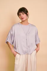 Blusa de satén color lila con escote en V y cierre frontal con botones.