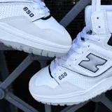 Championes de corte alto New Balance modelo 650, con diseño inspirado en el básquetbol. Presentan una combinación de cuero blanco y detalles en azul marino, con puntera de gamuza gris claro y suela de goma en tonos grises.