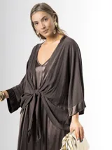 Kimono confeccionado en tejido liviano color marrón chocolate, con bordes satinados y mangas amplias. Puede usarse abierto o cerrado mediante un nudo al frente.