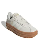 Championes Adidas modelo VL Court Bold con diseño de plataforma alta. Presentan una capellada de cuero en tono gris claro con las icónicas tres tiras laterales y detalles de marca en dorado. Cuentan con suela de goma color caramelo y cierre mediante cordones.