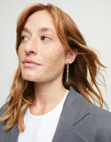 Par de aros colgantes dorados con eslabones de metal con forma de bolitas unidas entre sí.