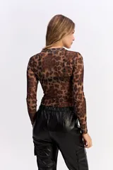 Body de manga larga confeccionado en tejido mesh transparente con estampado de lunares blancos sobre fondo negro. Presenta cuello alto y un diseño ajustado al cuerpo.