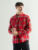 Camisa de franela a cuadros color celeste, gris y negro, de manga larga con dos bolsillos frontales con solapa abotonada.