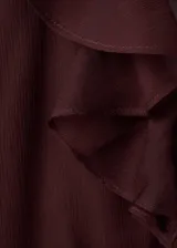 Blusa fluida color bordó, con escote en V, mangas largas con volantes en los puños y detalles de volantes en el frente y el cuello.