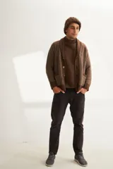 Cardigan marrón tejido con cuello smoking, cierre con botones y bolsillos delanteros. Tejido en 100% lana fina sin teñir.