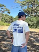 Remera beige de manga corta con estampado gráfico en azul en la espalda que incluye el texto "BROKERS GRAPHIC RESEARCHING" y "THE NEW WAVE BROKERS".