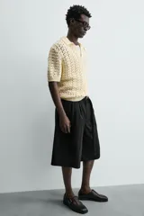 Bermuda negra de corte ancho (wide fit) con pliegues frontales, bolsillos laterales y bolsillos traseros de vivo.