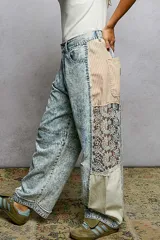 Pantalon tipo barrel en denim lavado claro con efecto acid wash, corte holgado y detalles combinados en los laterales con tela a rayas y encaje.