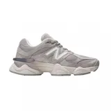 Championes urbanos New Balance modelo 9060, color gris con detalles en tonos más claros. Presentan un diseño robusto con capas superpuestas de gamuza y malla, y una entresuela esculpida con tecnología de amortiguación.