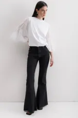 Jean de corte acampanado con cintura alta, confeccionado en denim azul oscuro. Presenta costuras en contraste y un acabado deshilachado en el ruedo.