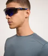 Remera deportiva de manga larga con cuello redondo, confeccionada en tejido técnico Dry Fit. Presenta un diseño liso en color negro con detalles reflectantes en los hombros.