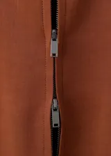 Chaqueta color marrón terracota de cuello camisero, manga larga, bolsillos laterales y cierre frontal con cremallera.