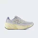 Championes de running New Balance modelo Fresh Foam More V5, color gris con detalles en lila y amarillo pálido. Presentan una entresuela Fresh Foam X sobredimensionada para máxima amortiguación, capellada de malla transpirable y ajuste mediante cordones.