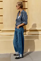 Jeans baggy de tiro medio con pernera holgada, diseño de cinco bolsillos y bajo acabado en vuelta. Cuenta con cintura elástica en la espalda y cierre frontal con cremallera y botón.