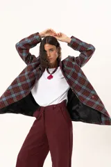 Blazer de corte oversize con estampado de cuadros en tonos azul, bordó y marrón. Presenta solapas clásicas, bolsillos con solapa en el frente y cierre frontal con botones.