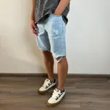 Bermuda de jean en color celeste claro con diseño de roturas y bordes deshilachados.