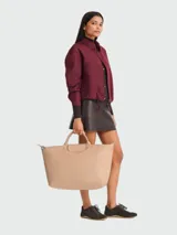 Bolso de viaje tipo tote de gran tamaño, color beige, con diseño minimalista, asas cortas superiores y cierre de cremallera con solapa de botón a presión.