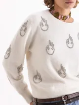 Sweater de tejido de punto gris con textura de pelo, cuello redondo y mangas largas. Presenta un bordado frontal de piedras brillantes con forma de flamas.