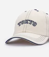 Gorra de sarga color blanco crudo, con visera curva, costuras contrastantes y bordado frontal con el texto "Tokyo" en color azul marino.