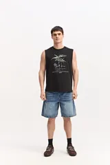 Musculosa oversize blanca de algodón, con sisas amplias y estampa frontal de inspiración tropical con palmeras y texto.
