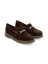 Mocasín de nobuck color marrón chocolate, con hebilla metálica dorada en el empeine, costuras visibles en el contorno y suela de PVC con plataforma leve.