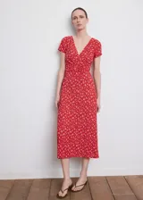 Vestido midi rojo con estampado floral blanco, cuello en V, manga corta y detalle de nudo frontal en el pecho.