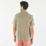 Camisa de manga corta color verde oliva con cuello clásico y cierre abotonado. Presenta un sutil estampado floral bordado en toda la prenda.