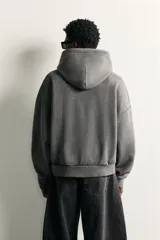 Sudadera con capucha de corte relajado, confeccionada en tejido de algodón con efecto lavado. Presenta manga larga, bolsillo frontal tipo canguro y terminaciones en rib.