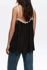 Top de diseño fluido en color negro con detalles de encaje blanco en el escote y tirantes finos regulables con lazos.